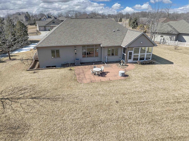 rear view of property featuring a lawn, a patio, cooling unit, roof with shingles, and a sunroom