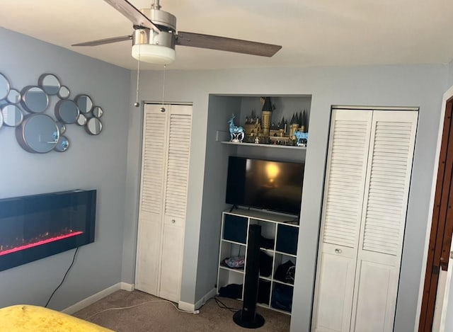 carpeted bedroom with a glass covered fireplace, a ceiling fan, and baseboards