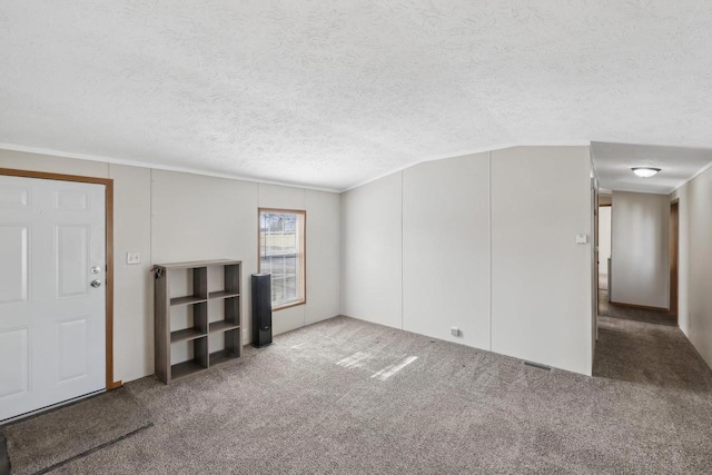 unfurnished living room featuring visible vents, a textured ceiling, carpet, and vaulted ceiling