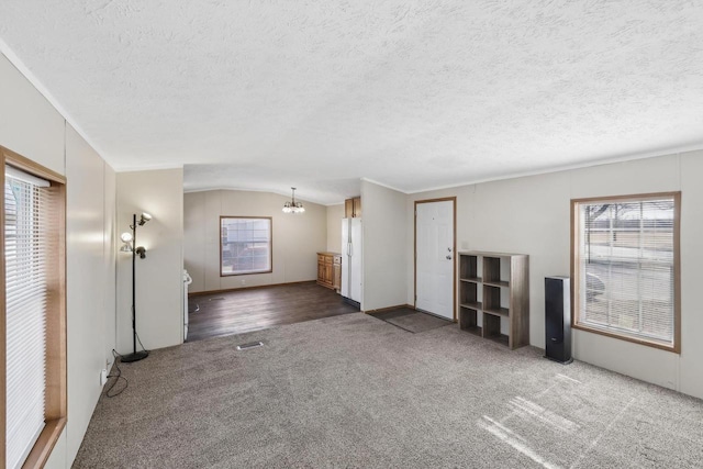 unfurnished living room featuring a notable chandelier, plenty of natural light, and lofted ceiling