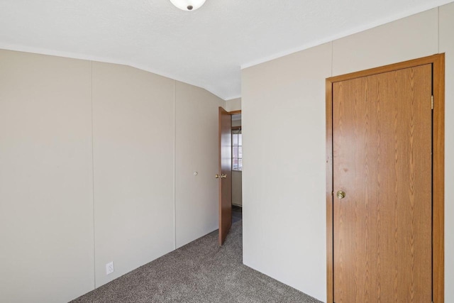 unfurnished bedroom featuring a closet, carpet floors, and vaulted ceiling