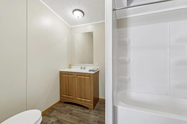 bathroom featuring vanity, wood finished floors, toilet, a textured ceiling, and a bath