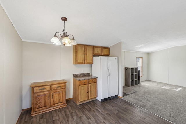 kitchen featuring brown cabinetry, freestanding refrigerator, ornamental molding, dark wood-type flooring, and a chandelier