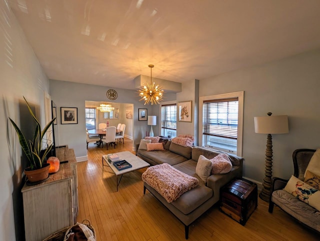 living room with baseboards, a chandelier, and hardwood / wood-style flooring