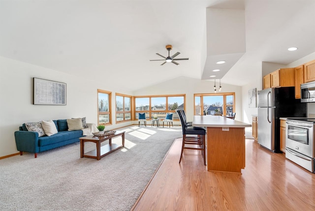 kitchen featuring open floor plan, light countertops, appliances with stainless steel finishes, a kitchen breakfast bar, and a ceiling fan