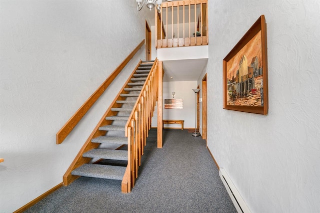 stairs with a baseboard heating unit, a textured wall, and carpet floors