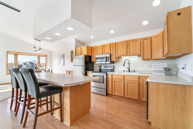 kitchen featuring lofted ceiling, a sink, stainless steel appliances, a kitchen breakfast bar, and a center island