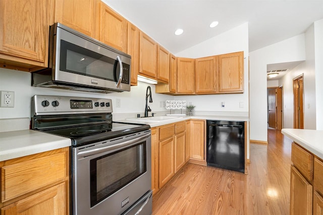 kitchen with light countertops, lofted ceiling, light wood-style flooring, stainless steel appliances, and a sink