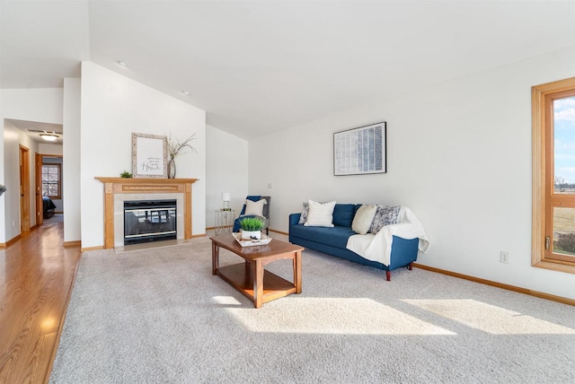 living room featuring a tiled fireplace, vaulted ceiling, wood finished floors, and baseboards