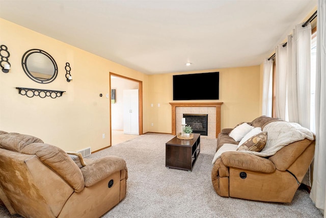 living area with visible vents, carpet floors, baseboards, and a tiled fireplace