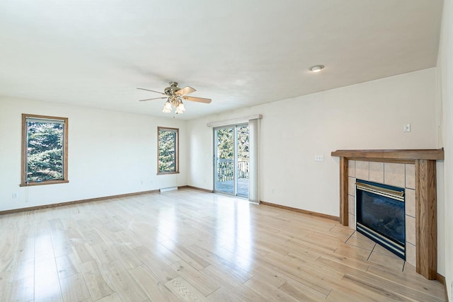 unfurnished living room with light wood-style flooring, baseboards, ceiling fan, and a tile fireplace