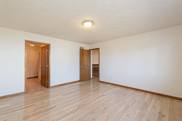 unfurnished room with baseboards and light wood finished floors