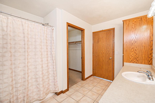 full bath with tile patterned flooring, a shower with curtain, baseboards, and a sink