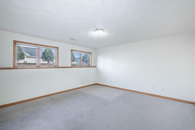 empty room with light carpet, visible vents, and baseboards