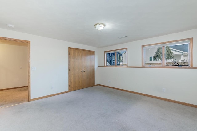 unfurnished bedroom with a closet, baseboards, light colored carpet, and visible vents