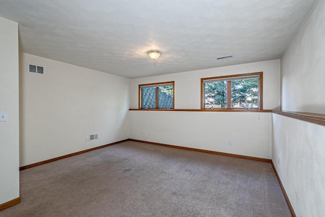 empty room with visible vents, carpet floors, and baseboards