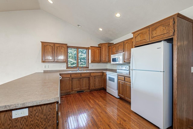 kitchen with a sink, dark wood finished floors, white appliances, a peninsula, and brown cabinetry