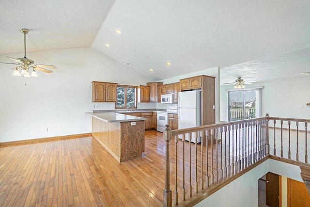 kitchen featuring brown cabinetry, white appliances, a peninsula, and a ceiling fan