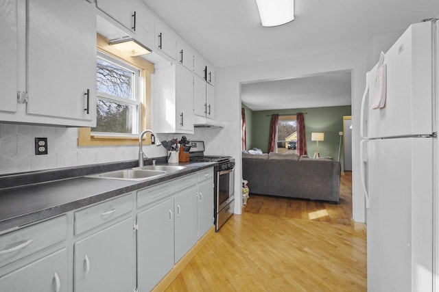 kitchen with stainless steel gas stove, a sink, plenty of natural light, dark countertops, and freestanding refrigerator