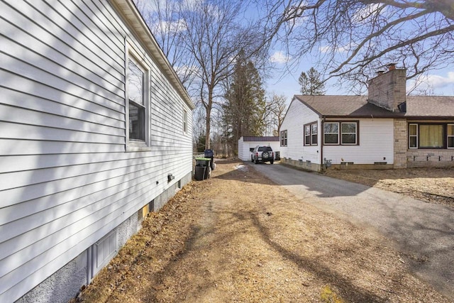 view of side of property featuring aphalt driveway and an outdoor structure