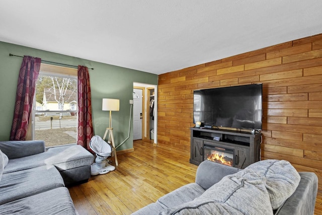 living room with a glass covered fireplace, wood finished floors, and wood walls