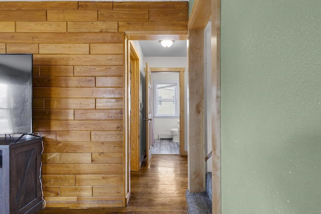 hall with wooden walls, wood finished floors, and baseboard heating