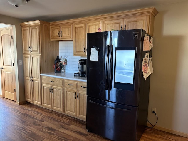 kitchen with dark wood-style floors, freestanding refrigerator, light countertops, decorative backsplash, and baseboards