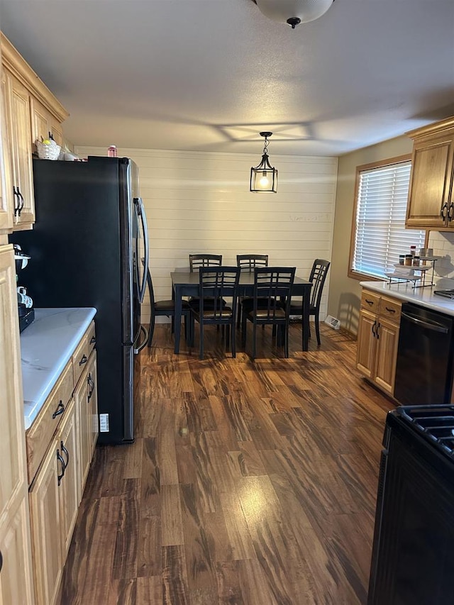 kitchen featuring pendant lighting, black appliances, dark wood-type flooring, and light countertops