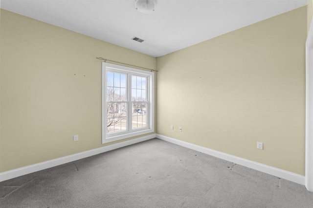 spare room with carpet flooring, baseboards, and visible vents