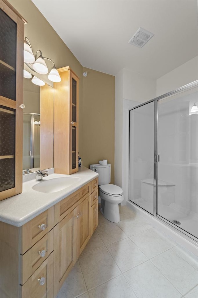 bathroom featuring visible vents, toilet, a stall shower, tile patterned floors, and vanity