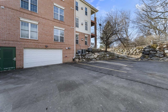 exterior space with driveway, central AC, and an attached garage