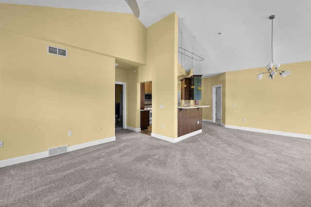 unfurnished living room featuring baseboards, visible vents, carpet floors, and high vaulted ceiling