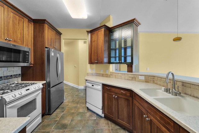 kitchen featuring a sink, stainless steel appliances, light countertops, decorative light fixtures, and tasteful backsplash