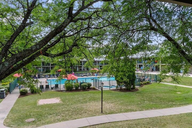 surrounding community featuring a swimming pool, a yard, and fence