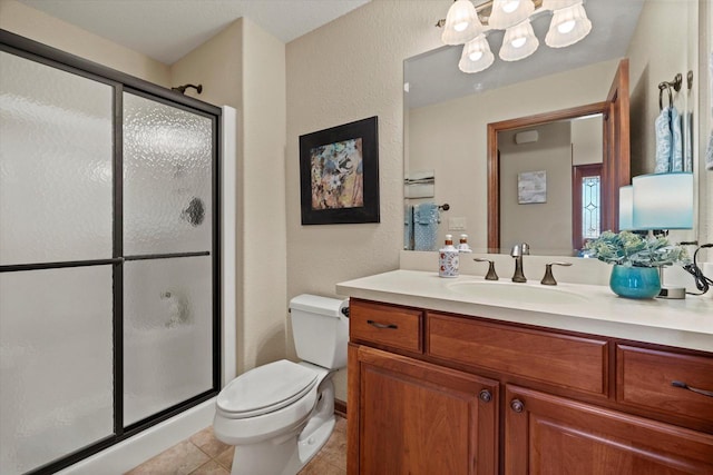 bathroom with tile patterned flooring, a shower stall, toilet, a textured wall, and vanity