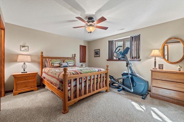 carpeted bedroom with visible vents, a textured ceiling, ceiling fan, and a textured wall