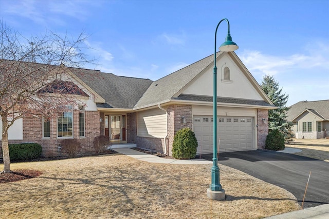 view of front facade featuring brick siding, a shingled roof, aphalt driveway, and a garage