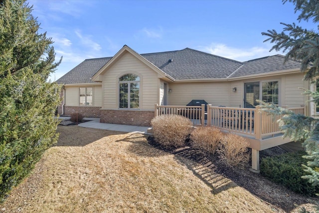 rear view of property featuring brick siding and a shingled roof