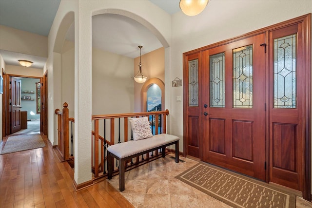 entrance foyer featuring baseboards, arched walkways, and hardwood / wood-style flooring