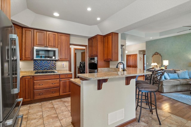 kitchen featuring visible vents, stainless steel appliances, a raised ceiling, and open floor plan