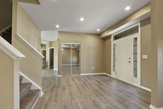 foyer entrance with stairs, recessed lighting, wood finished floors, and baseboards