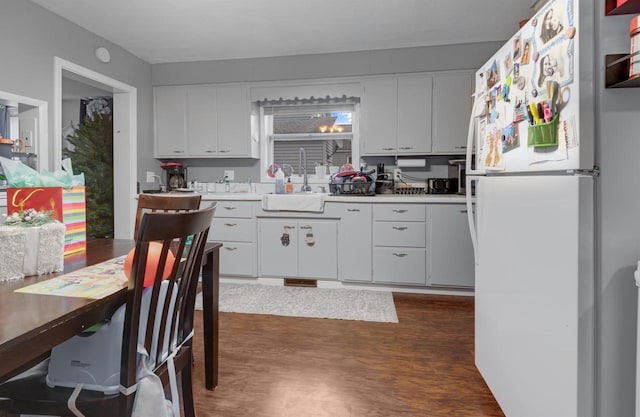 kitchen with a sink, dark wood finished floors, freestanding refrigerator, white cabinets, and light countertops