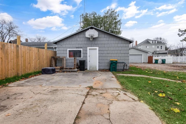 rear view of property with a garage, an outbuilding, and fence