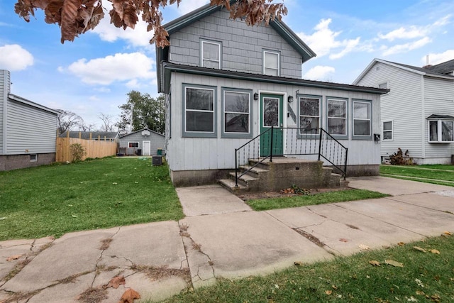 view of front of home featuring a front yard, central AC unit, and fence