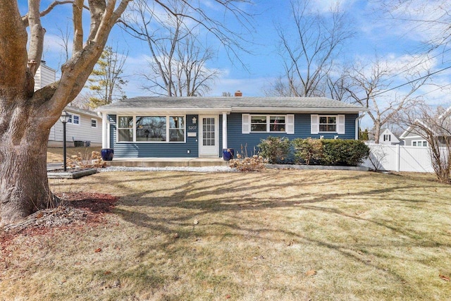 single story home with a chimney, a front yard, and fence