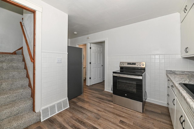 kitchen featuring stainless steel appliances, tile walls, visible vents, and white cabinetry