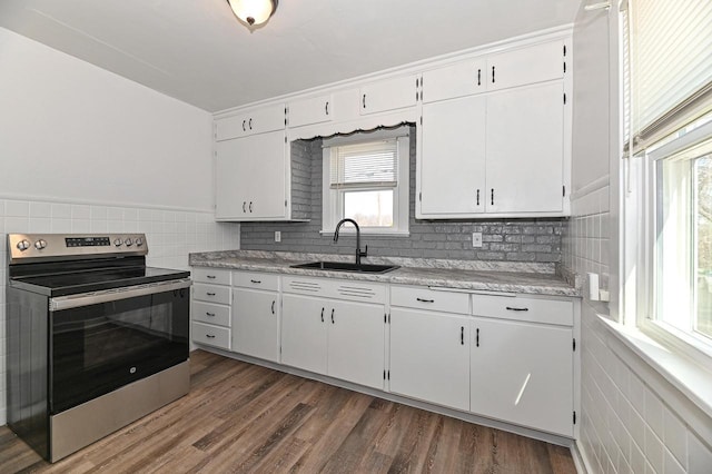 kitchen featuring stainless steel electric range, light countertops, dark wood-type flooring, and a sink