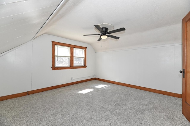 additional living space with baseboards, carpet, lofted ceiling, a textured ceiling, and a ceiling fan