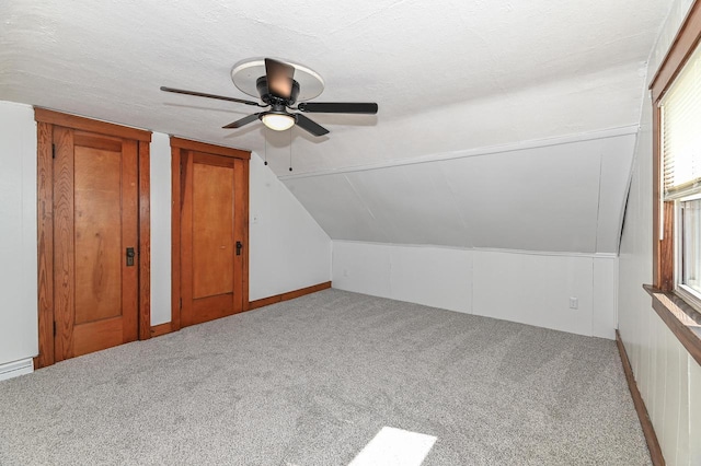 additional living space with vaulted ceiling, carpet flooring, a ceiling fan, and a textured ceiling