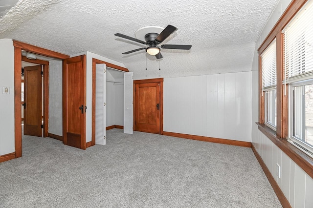 unfurnished bedroom featuring a textured ceiling, a closet, carpet floors, baseboards, and ceiling fan